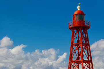 Red lighthouse on blue sky background