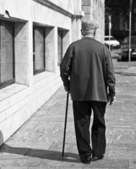 Anciano con bastón y gorra paseando