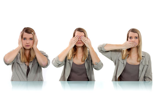 woman covering her eyes, ears and mouth with her hands