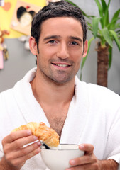 Man dipping croissant in coffee
