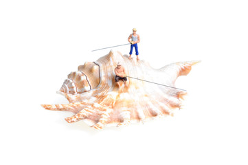 tiny figures of anglers with fishing rods on a seashell