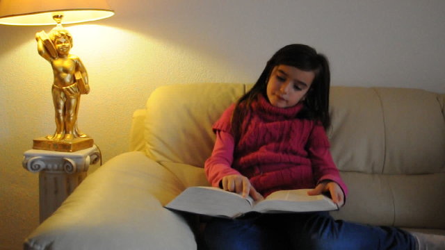 Mädchen liest ein Buch auf dem Sofa