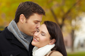 Mann küsst Frau im Park