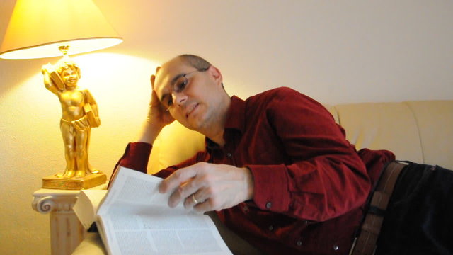 Mann liest ein Buch auf dem Sofa