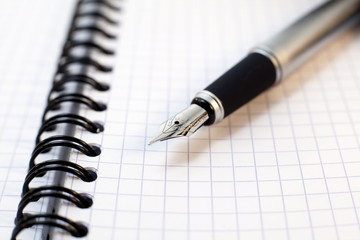 stylo plume posé sur un bloc de notes a spirales