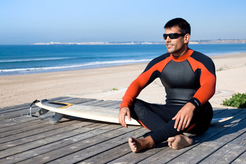 Surfer wearing a wetsuit with surf board.