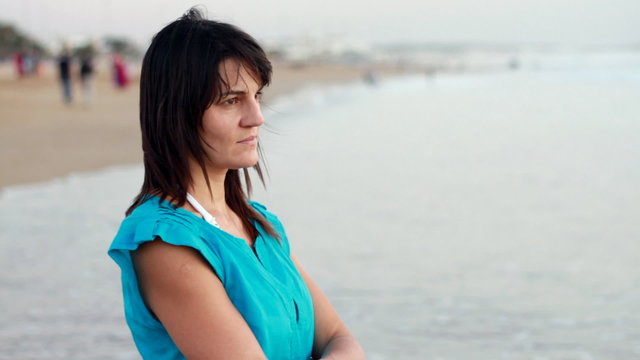 Sad pensive woman standing on the beach, steadicam shot