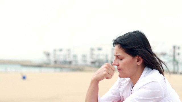 Sad pensive woman sitting by the beach, outdoors