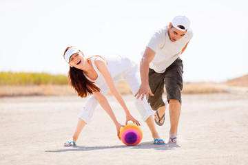 Happy couple playing with colorful ball; white sky background
