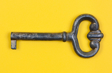 Antique key close-up on yellow background.
