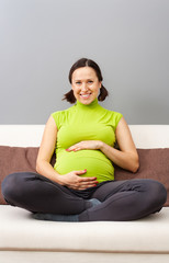 Fototapeta na wymiar smiley pregnant woman sitting on sofa