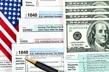 Tax forms with pen, money and U.S. flag.