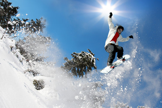 Snowboarder jumping against blue sky