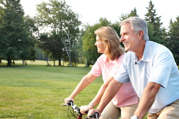 Senior couple cycling in park.