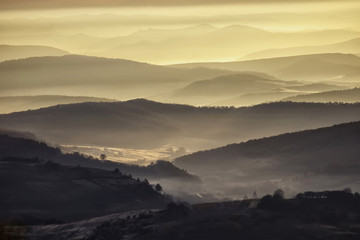 valley in a beautiful early morning with fog and hills
