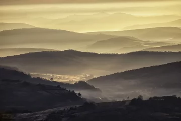Fototapeten valley in a beautiful early morning with fog and hills © andreiuc88