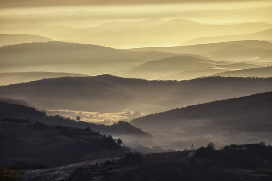 Fototapeta valley in a beautiful early morning with fog and hills