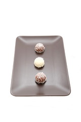 Chocolate and coconut balls on brown plate