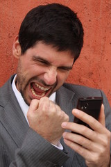 Businessman holds his cmartphone and celebrates