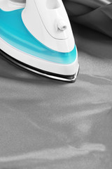 Electric iron on grey cloth closeup