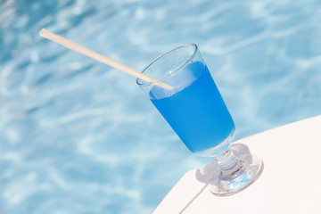 Freshening cocktail of blue color against water pool