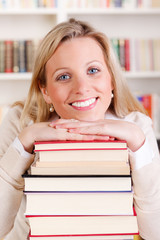 junge frau stützt sich auf einen stapel bücher