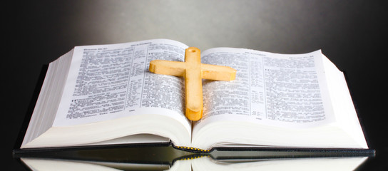 Russian open holy bible with wooden cross on black backround