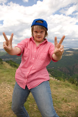 A girl with Down syndrome making victory sign.