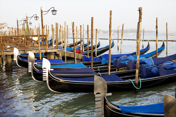 Fototapeta na wymiar Gondolas tied to wooden poles in Venice, Italy