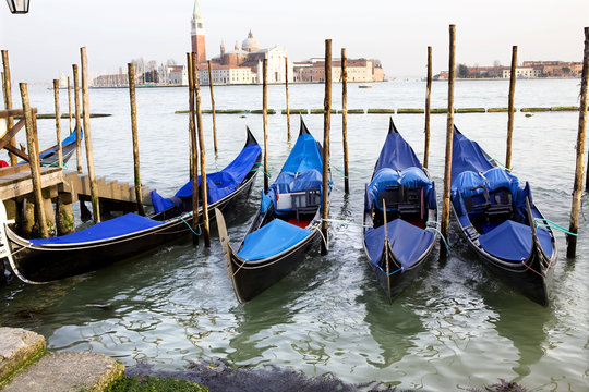 Gondolas tied to wooden poles in Venice, Italy
