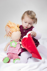 kleines Mädchen zieht Puppe eine Nikolaus Mütze an