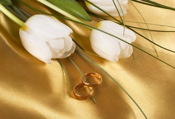 wedding rings and white tulips on light silk