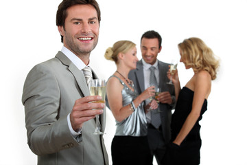 Man holding champagne glass with friends in background