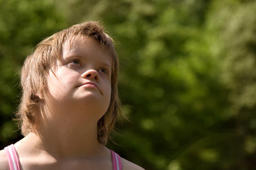 A girl with Down syndrome in nature looking up