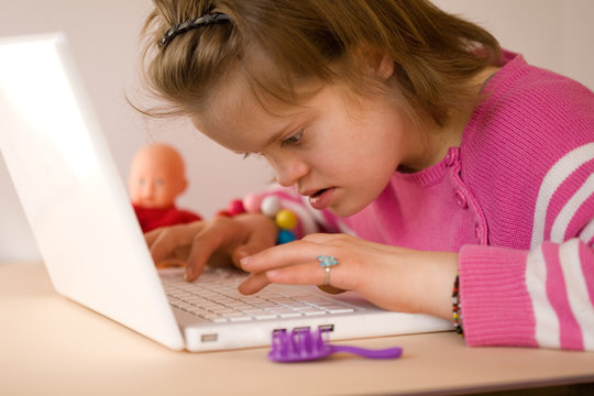 A girl with Down syndrome using a laptop.