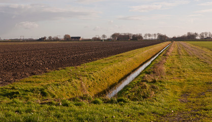 Fototapeta na wymiar Holenderski krajobraz zimowy z rowu i zaorane pole
