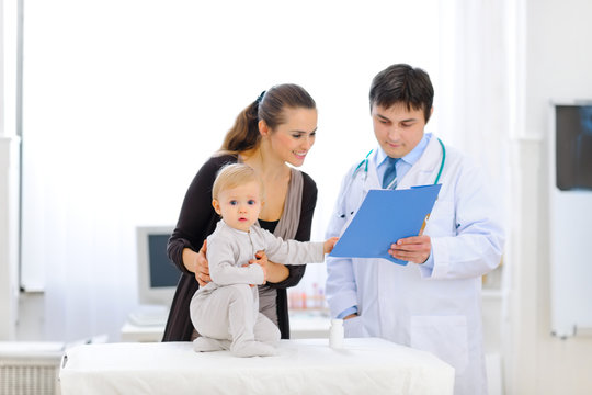 Baby touching card while pediatrician talking with mother