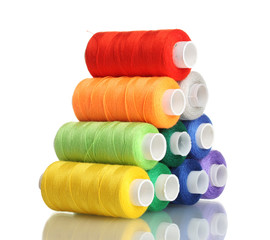 Pyramid of many-coloured bobbins of thread isolated on white