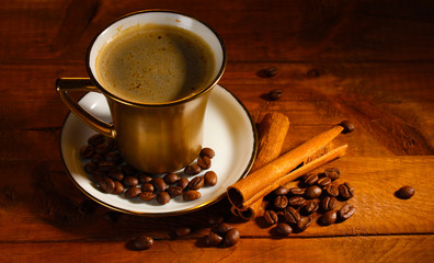 golden cup with coffee, cinnamon and coffee beans