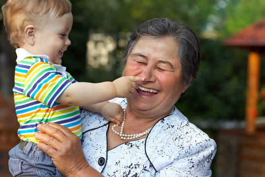 Cute Grandson Grabbing Nose Of Laughing Great Grandmother