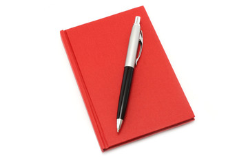 Naklejka premium Red notepad with ball pen on a white background