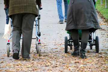 Altes Paar mit Gehwagen und Kinderwagen im Park