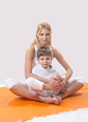 A beautiful young mother practices yoga with her son