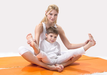 A beautiful young mother practices yoga with her son