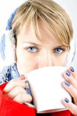 Blue-eyed girl dressed in winter clothes drinks a coffee.