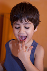 bambino che lecca dita piena di crema di cioccolato