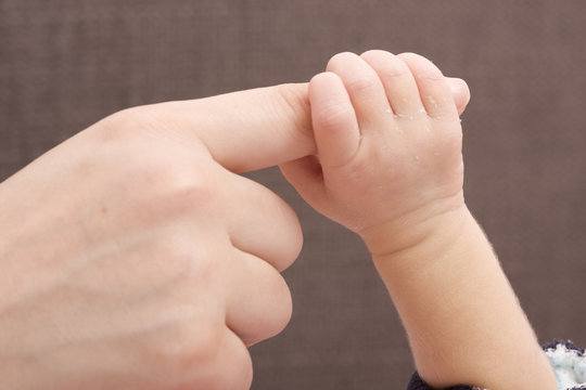 Close-up of baby's hand holding mother's finger