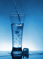 Water flows into the glass with ice