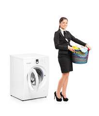 Smiling woman holding a laundry basket next to a washing machine