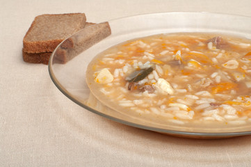 Plate of soup and slices of rye bread close up.